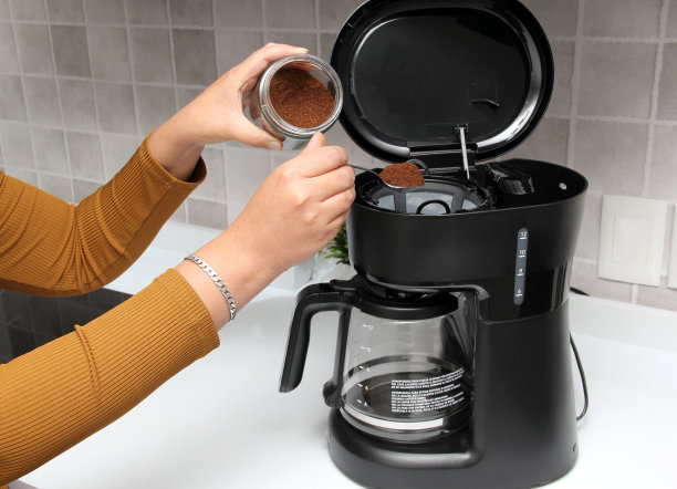 女人的双手在厨房的咖啡机里用清水和现磨咖啡为早餐准备美味而芳香的咖啡图片下载