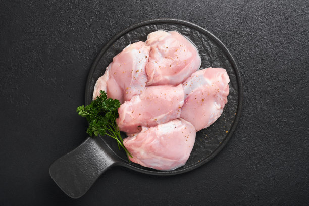 无皮生鸡腿肉片，黑色底色放香草和香料。农场禽肉。带有复制空间的俯视图。模拟。图片下载