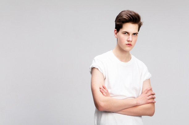 穿着白色t恤的年轻人看着灰色背景下的相机图片下载