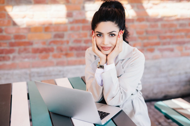 穿着白大褂，涂着红色指甲的迷人年轻女子，用笔记本电脑，在高速免费互联网上与家人聊天。图片下载