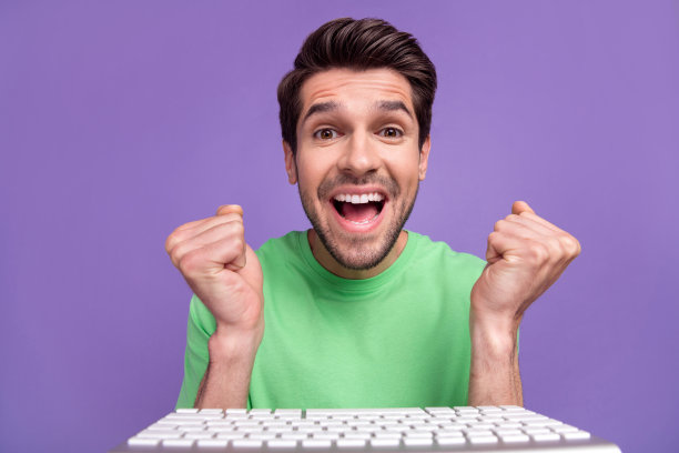 特写摄像头干部的年轻人拳头庆祝胜利赌博网上大收入利润附近键盘极客孤立在紫色的背景图片下载