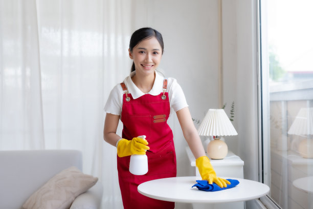 戴着手套、系着围裙的亚洲主妇正在愉快地打扫房间。快乐的亚洲年轻女子正在拖地。图片下载