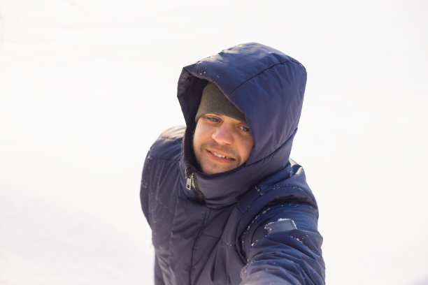 一名穿着冬衣的男子伸出手帮助他下到白雪皑皑的湖边。欧洲白种人微笑男人生活方式肖像，积极情绪。帮助的概念图片下载