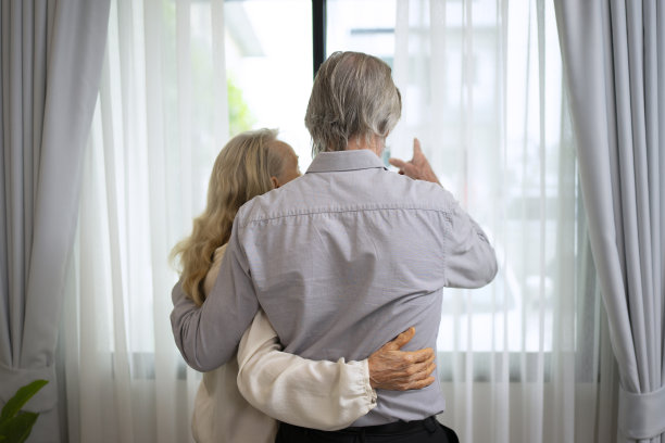 一对年长的夫妇拥抱在一起，向外看。图片下载