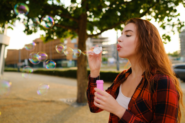 年轻女子站在街上吹肥皂泡玩得很开心图片下载