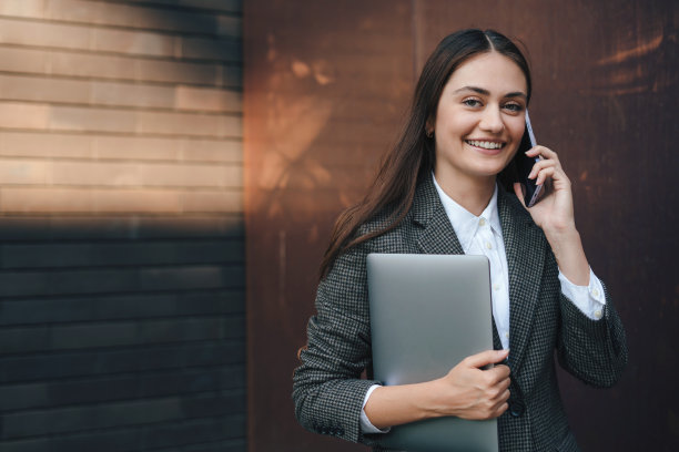 一个成功的商业女性在阳光明媚的日子里用手机聊天，漫步在城市的户外。在线交流。在线商务演讲者。成功的事业。图片下载