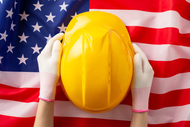 劳动节感谢女职工。在美国国旗的背景下，女性戴着工作手套，戴着安全帽。和我们一起做广告图片下载