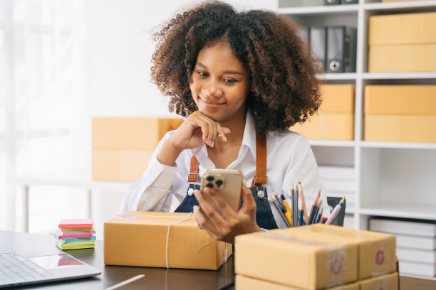 创业或小型企业企业家在电子商务，或物流在远程启动在家里。非裔美籍女店主在网上销售中小企业，运箱子，开店成功。图片下载