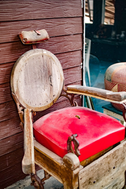 木墙旁边放着一把用木头和红色皮革做的旧椅子。图片下载