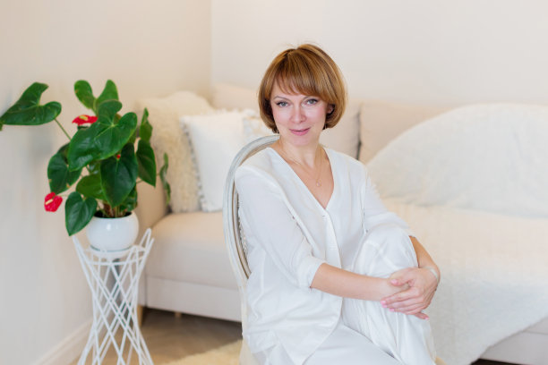 微笑的时尚成熟的中年妇女坐在家里客厅的椅子上休息。图片下载