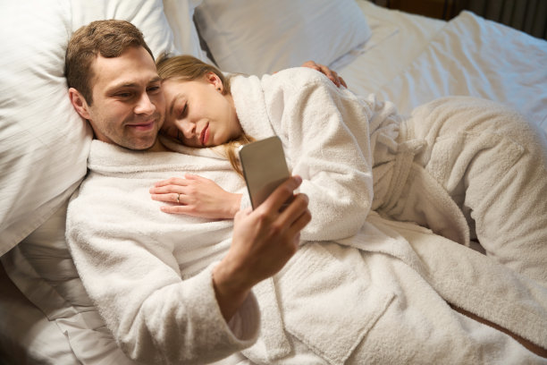男人在社交网络上聊天，而他的妻子睡在他的肩膀上图片下载