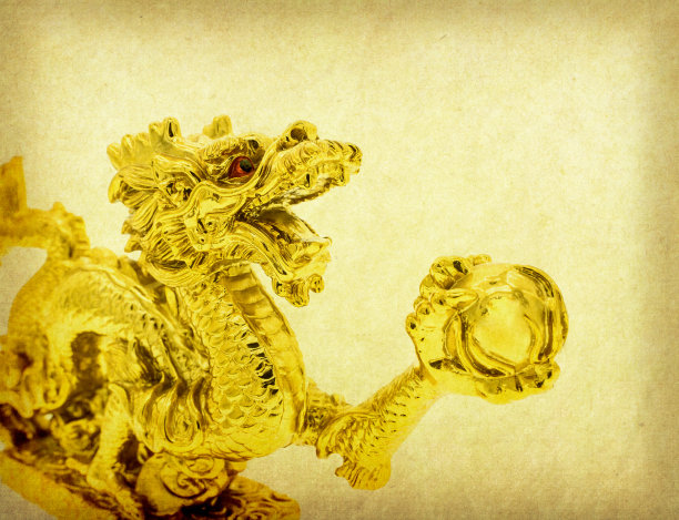 传统的黄金中国龙雕像在旧纸背景图片下载