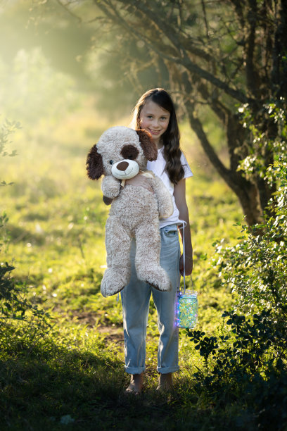年轻的女孩站着，拿着她的泰迪熊和灯笼图片下载