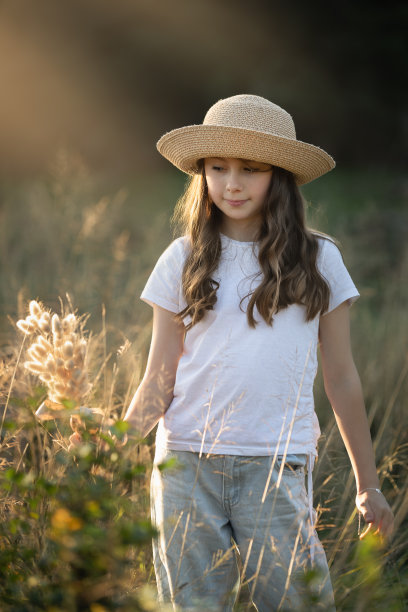日落时分，小女孩戴着帽子，捧着一束干草图片下载