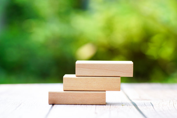 3堆叠矩形空木块在桌子上与绿色自然模糊背景为自己的客户文字或字母。有环保、能源或商业理念。正面视图，横幅复制空间。图片下载