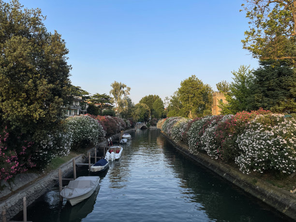 从意大利威尼斯丽都的四喷泉桥(Ponte delle Quattro Fontane)上看运河的特写图片，色彩缤纷的建筑，系泊的船只，湛蓝晴朗的天空，逐渐缩小的视角图片下载