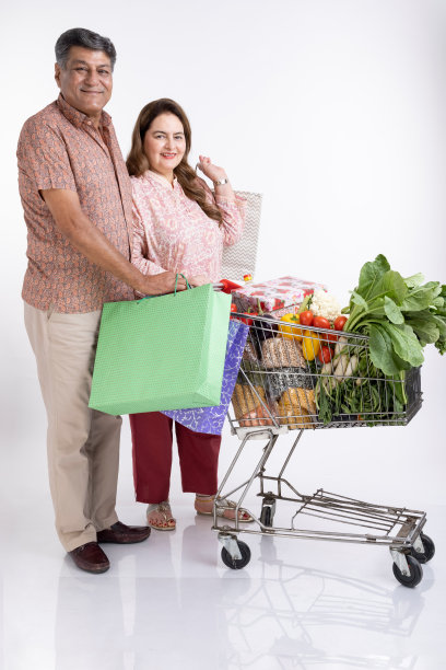 一对老年夫妇在白色背景上与购物车合影。图片下载