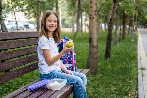 在公园里吃午餐三明治和苹果的女学生图片下载