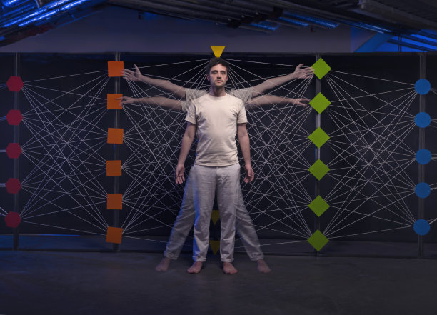 一个人站在一个抽象的框架前，手臂和腿伸向多个方向——类似于达芬奇的《维特鲁威人》——连接节点。“人工智能”的象征性代表。图片下载