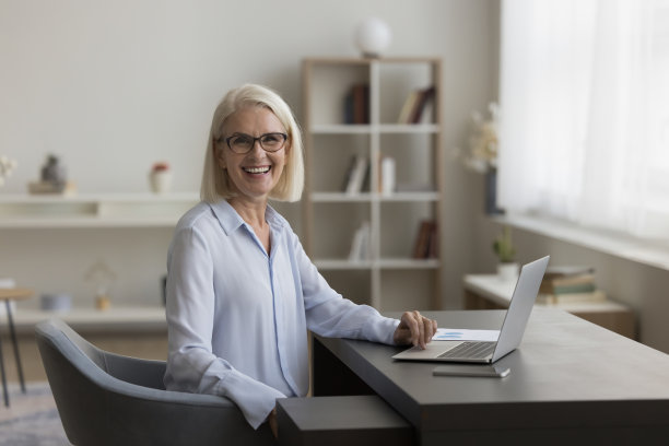 乐观的资深自由职业女性戴着眼镜在家里摆姿势图片下载