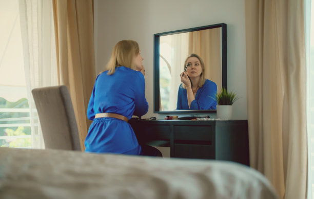 在家里对着镜子化妆的女人。图片下载