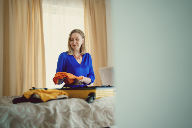 女人正在把衣服装进手提箱。为旅行做准备。图片下载