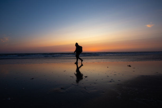 在葡萄牙布拉加的欧菲尔海滩，日落时分，朝圣者的剪影走向“圣地亚哥德孔波斯特拉”。图片下载