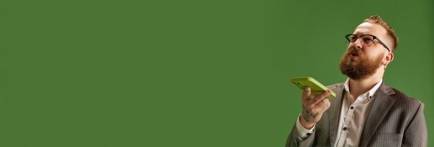 戴眼镜的严肃商人在绿色的工作室背景下用手机录制语音信息图片下载