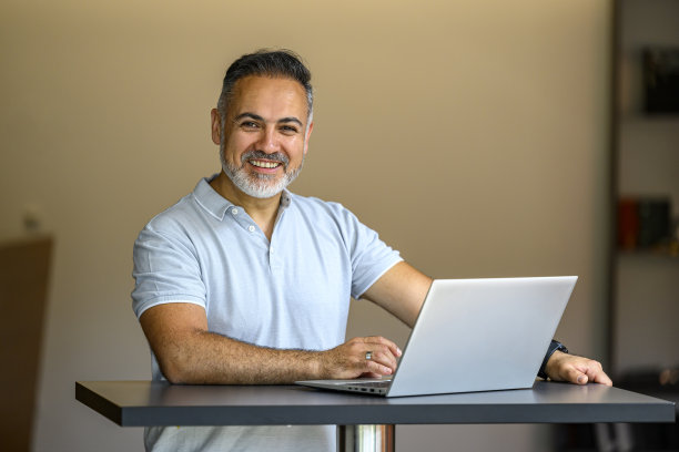 一个面带微笑的成熟商人在笔记本电脑前工作的画像图片下载