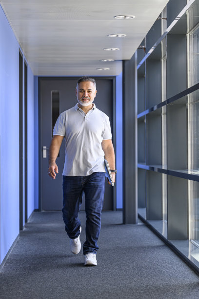 面带微笑的商人拿着笔记本电脑走在走廊里图片下载