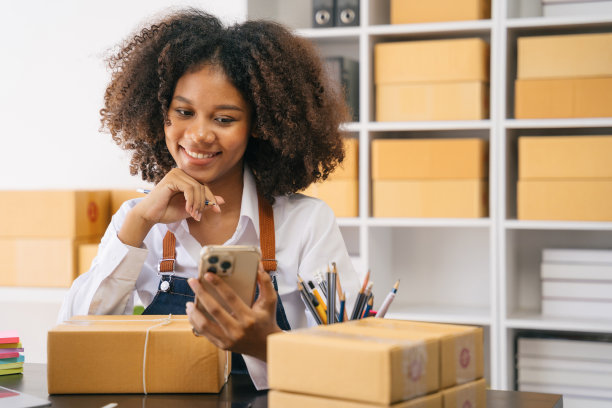 创业或小型企业企业家在电子商务，或物流在远程启动在家里。非裔美籍女店主在网上销售中小企业，运箱子，开店成功。图片下载