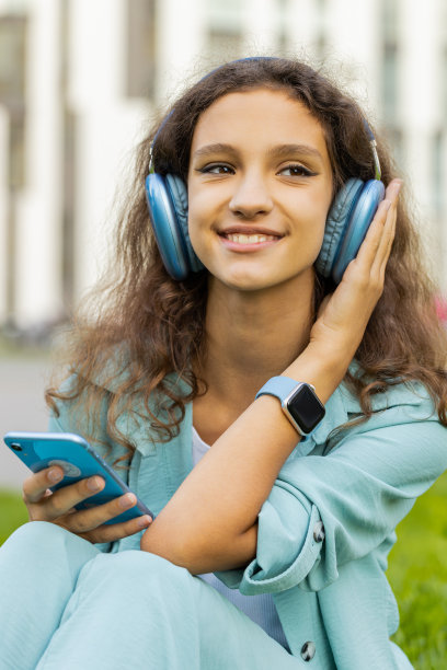 快乐的青春期前女孩戴着无线耳机选择，用智能手机听音乐在户外跳舞图片下载