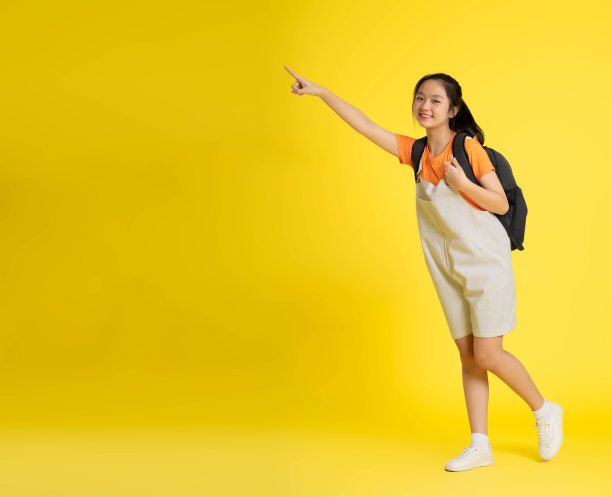 美丽的亚洲女学生的肖像，在黄色背景上背着双肩包图片下载