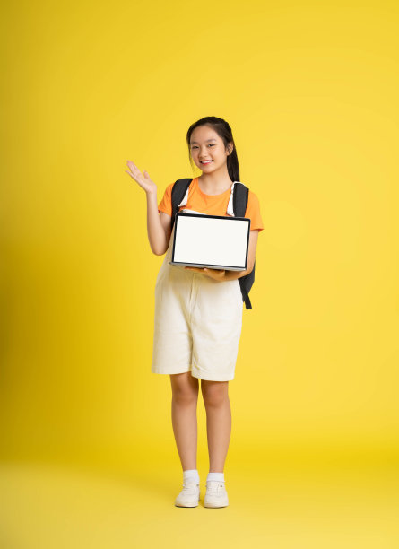 漂亮的亚洲女学生用黄色背景的笔记本电脑图片下载