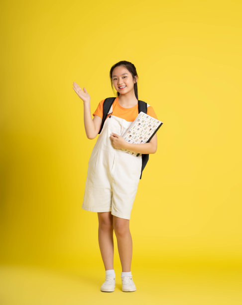 美丽的亚洲女学生的肖像，在黄色背景上背着双肩包图片下载