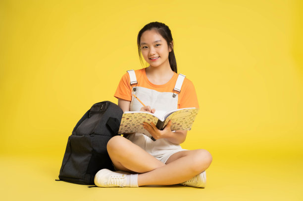 漂亮的亚洲女学生在黄色背景上摆姿势图片下载