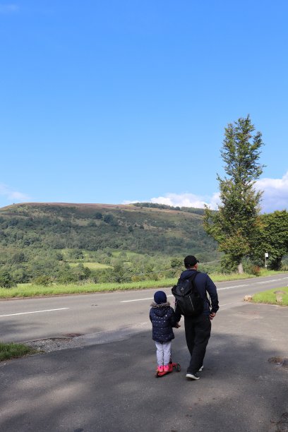 在阳光明媚的日子里，一家人在风景优美的山间散步。图片下载