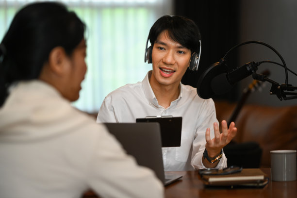 男主播戴着耳机在家庭工作室录制播客。广播，播客，博客和技术概念。图片下载