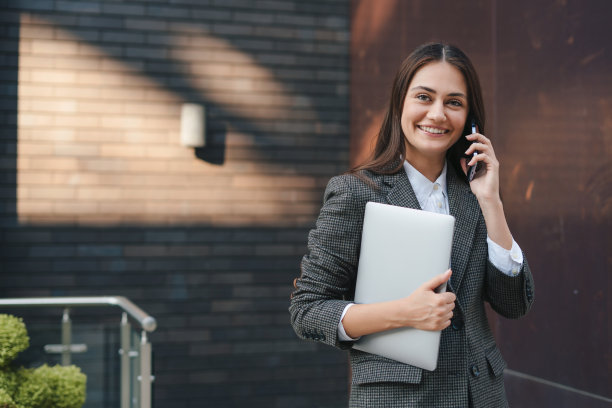 一个女商人走在街上用智能手机说话的照片。女经理在外面打电话。移动电话通讯。图片下载