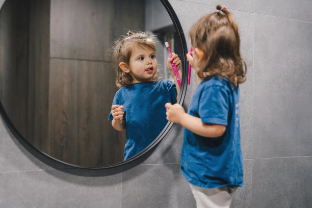 小女孩一大早刷牙，照镜子。浴室。镜面反射图片下载