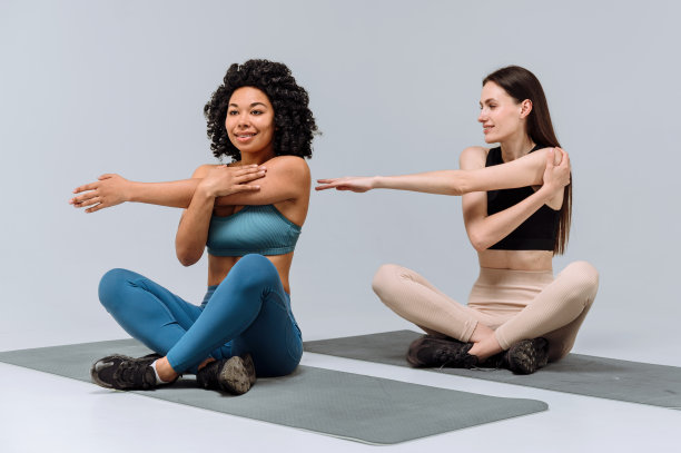 两名女子穿着运动服热身上身，伸展双手图片下载