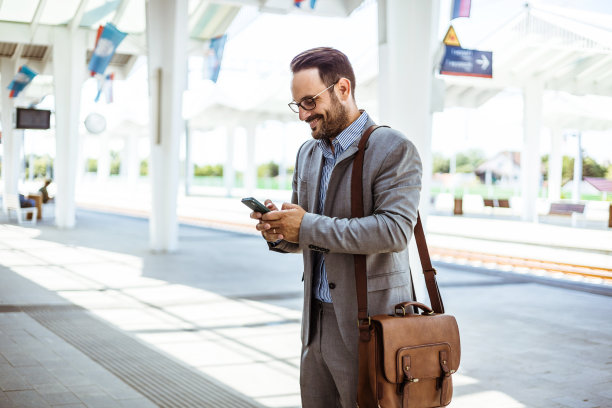 一个人在火车站用他的智能手机使用移动应用程序，商务旅行。图片下载