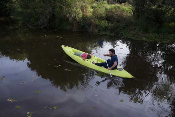 父子俩划着皮艇在小溪中划行图片下载