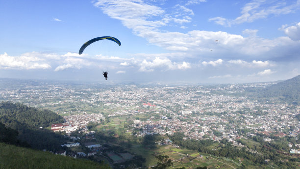 滑翔伞飞行高于村庄的看法和蓝天背景图片下载