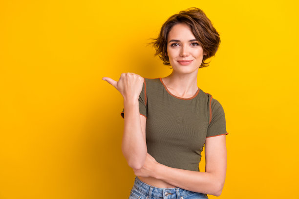 照片积极开朗可爱的漂亮女孩穿着卡其布t恤，表明在折扣空空间孤立的黄色背景图片下载