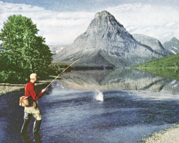 在山边的湖中涉水的渔夫图片下载