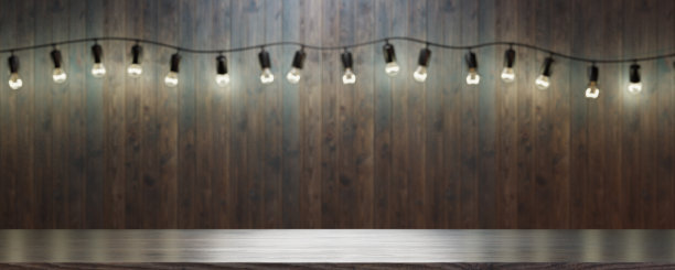 酒吧或餐馆里的空木桌。在酒吧或餐厅的墙上挂一串玻璃灯泡，这是你工作或留言的地方。3 d渲染。图片下载