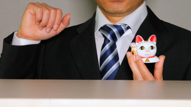 一个商人摆出和一只招手的猫一样的姿势图片下载