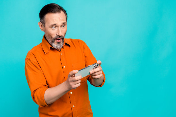 有趣的中年工作企业家拿着手机玩游戏成瘾的照片集中隔离在海蓝宝石色的背景图片下载