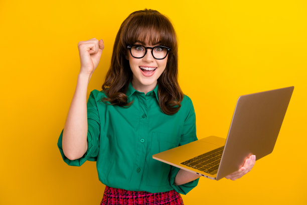 可爱的幸运女士穿着绿色衬衫赢得游戏的照片现代小工具孤立的黄色背景图片下载